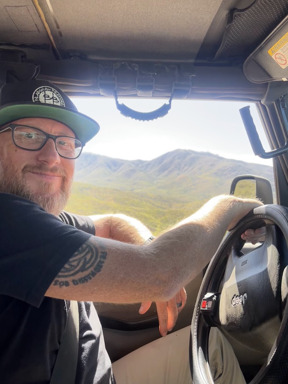 Man driving a vehicle with mountains in the background